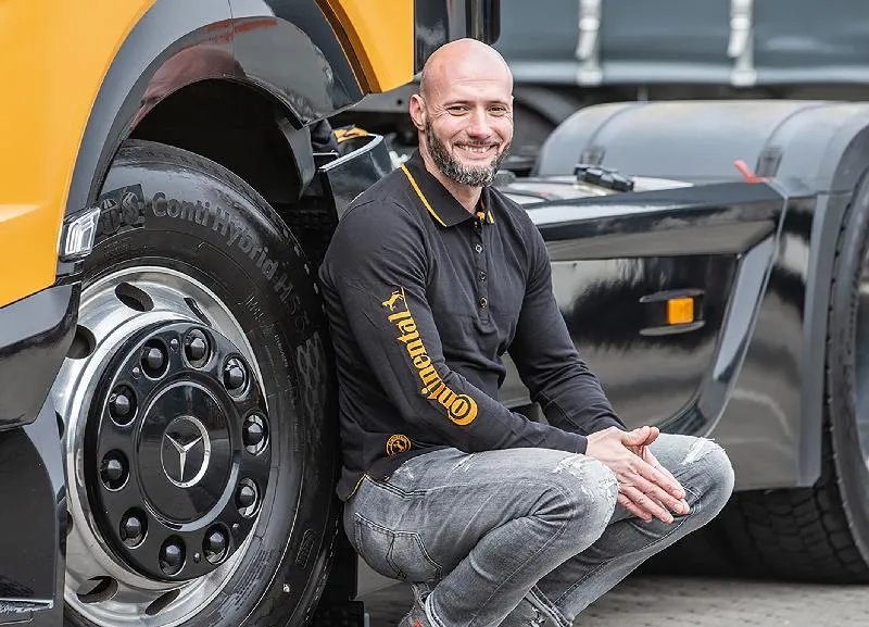 Professional truck driver Ronny Nittmann posing infront of the wheel of the show Truck he drives for the Continental roadshow blog