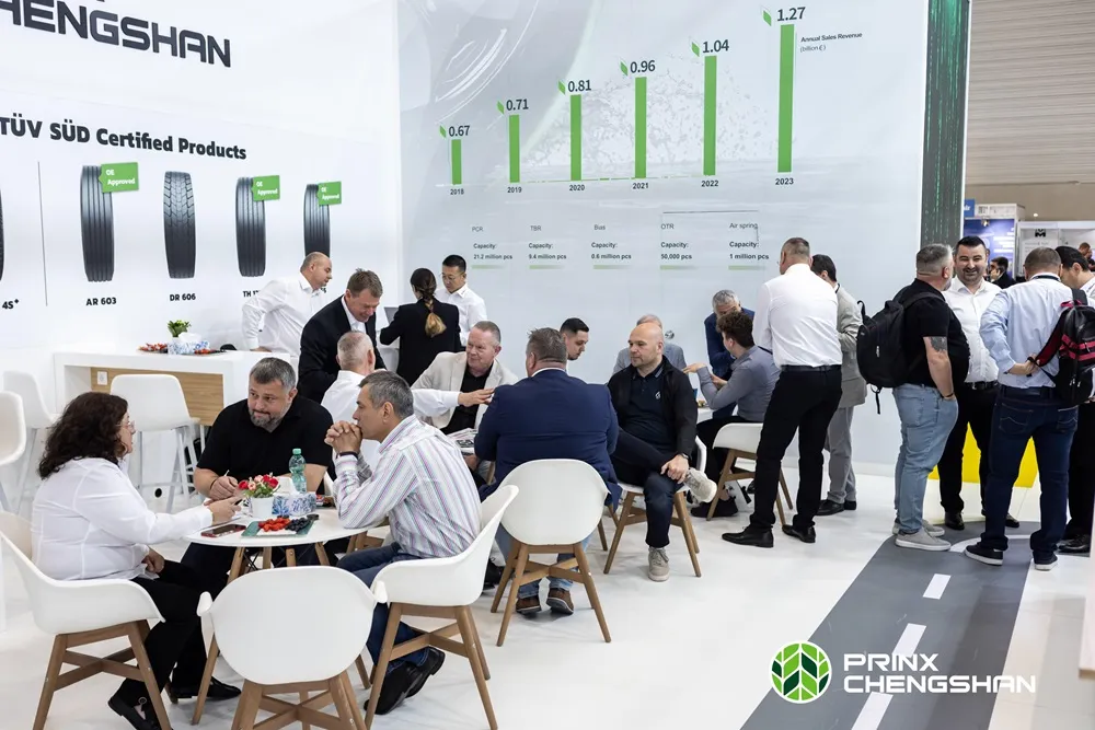 PRINX Exhibition at the Tire Cologne 2024. It features a white background with lots of people on chairs and tables talking.