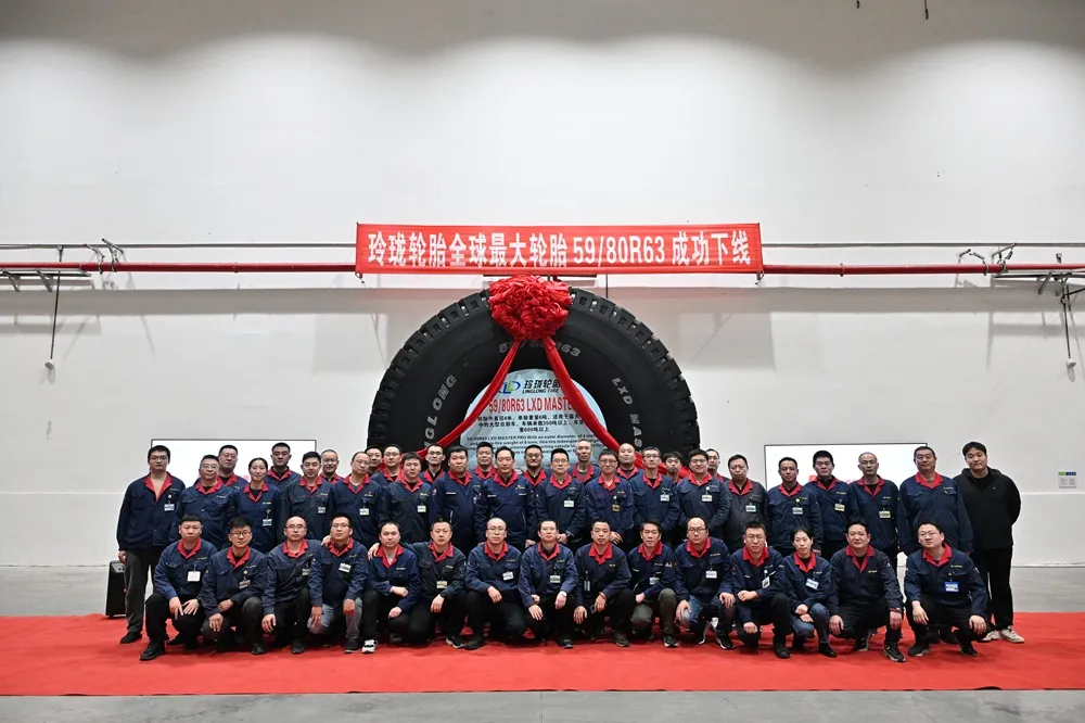 Image of Linglong Tire's new OTR Tyre with Linglong's employees stood and sat in front of it on a red carpet