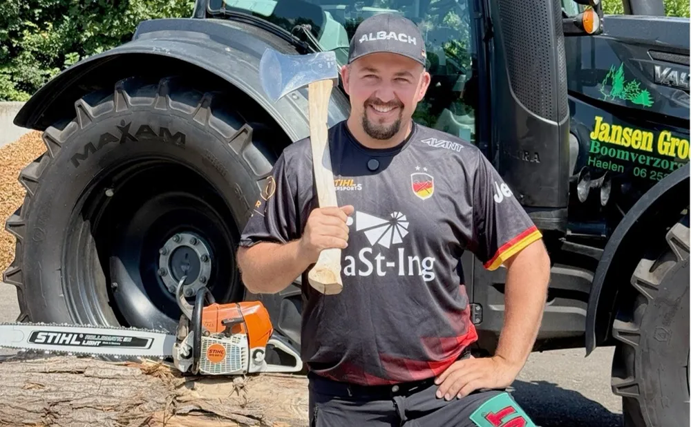 Image of a man holding an axe stood in front of a tractor